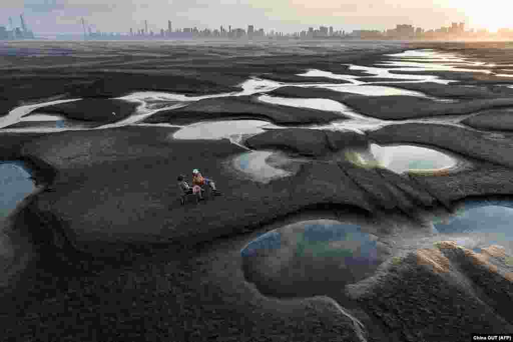 Людзі сядзяць на дне рэчышча перасохлай ракі Янзцы ў Кітаі. 2 верасьня 2022&nbsp;