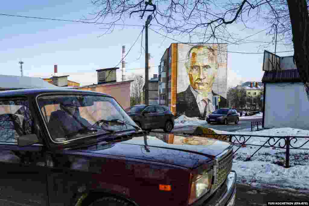 A man drives past a mural depicting Russian President Vladimir Putin on the side of an apartment building in Kashira, Moscow region, Russia.&nbsp;