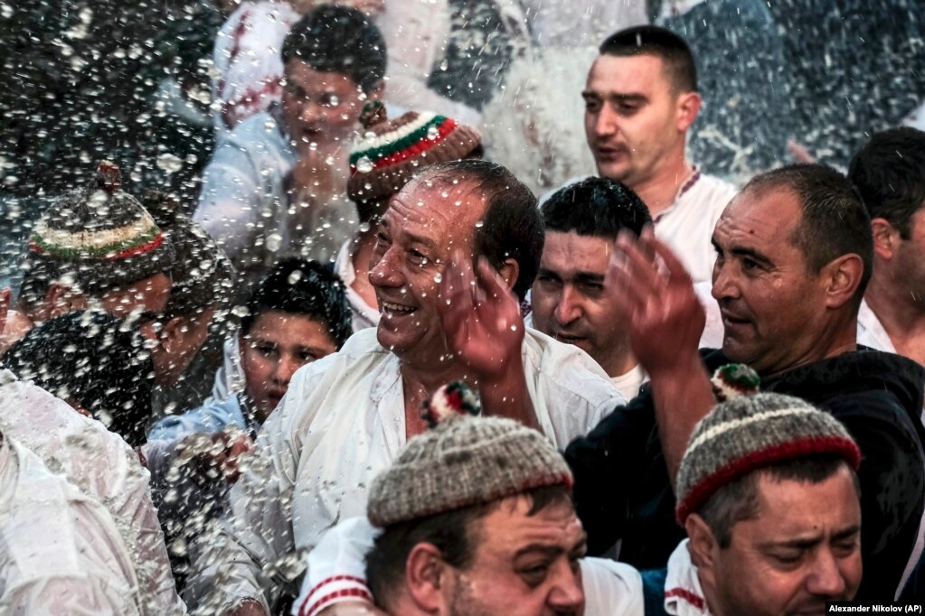 Një burrë shihet duke qeshur teksa të tjerët shihen duke spërkatur ujin në kuadër të një vallëzimi tradicional që bëjnë banorët e qytezës Kalofer të Bullgarisë.