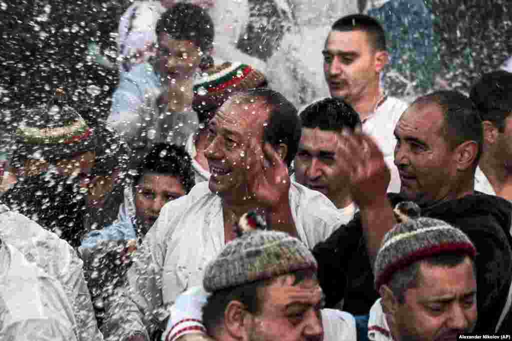 Мужчына усьміхаецца праз падчас традыцыйнага танца ў халоднай рацэ Тунджа падчас рытуалу Вадохрышча ў горадзе Калофер, Баўгарыя.
