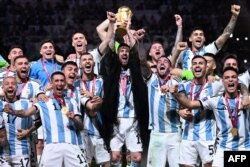 Lionel Messi ridică trofeul Cupei Mondiale, înconjurat de colegii săi, fiind îmbrăcat într-o mantie tradițională din lumea arabă, Doha, Qatar, 18 decembrie 2022.