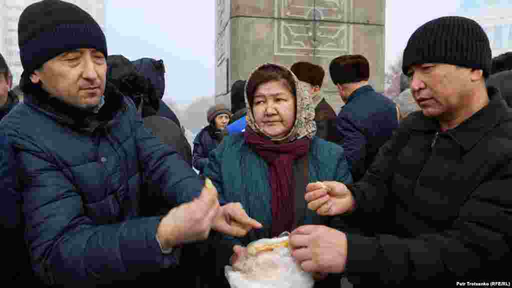 Женщина раздает лепёшки после молитвы у монумента Независимости