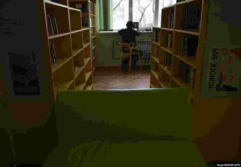 A man works on his laptop among the bookshelves at the library. &quot;As soon as the library reopened, we gave people the opportunity to recharge their phones. We gave people the opportunity to stay in warm conditions while watching the city rebuild,&quot; said Yevhenia Antonyuk of the Irpin city council.