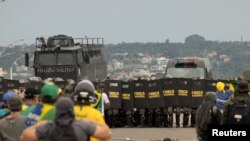 Kordon bezbednosnih snaga i pristalice bivšeg predsednika Brazila Žaira Bolsonara koje demonstriraju protiv predsednika Luiza Inacia Lule da Silve, u Braziliji, Brazil, 8. januara 2023.