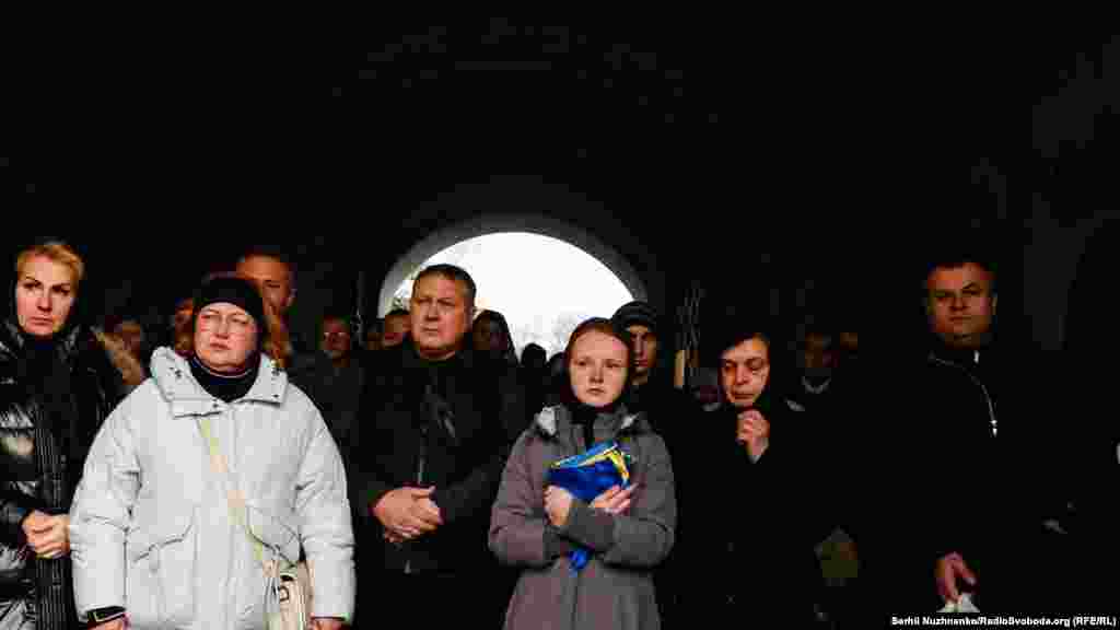 Жена Людмила держит украинский флаг, которым был накрыт гроб во время церемонии прощания