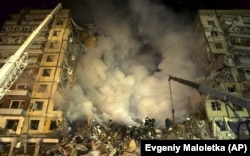 Spasioci čiste ostatke stambene zgrade nakon ruskog raketnog napada u Dnjipru, 14. siječnja 2023.