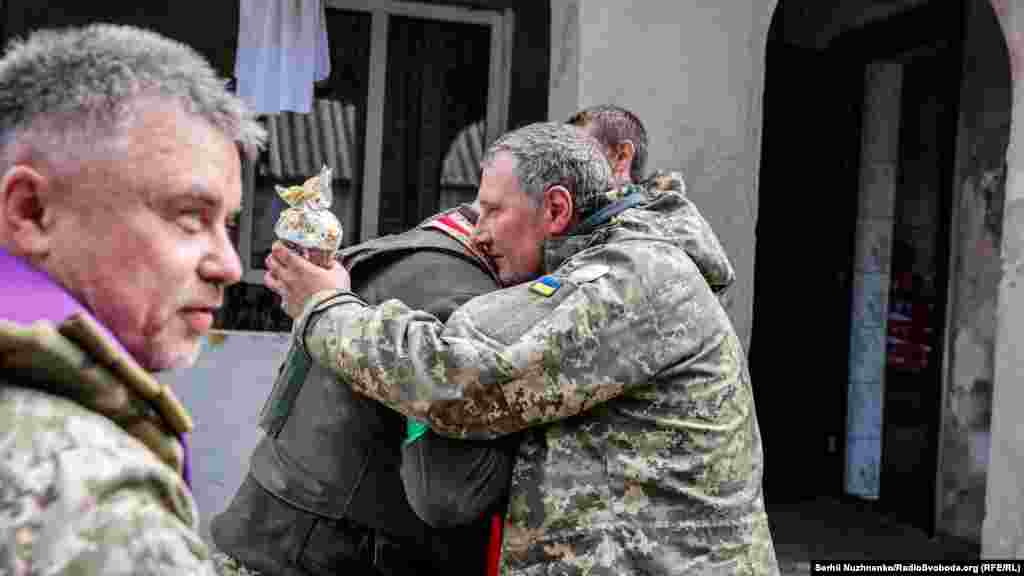 Військовий капелан Максим обіймає українського військового після Великоднього богослужіння. Харківська область, 24 квітня 2022 року
