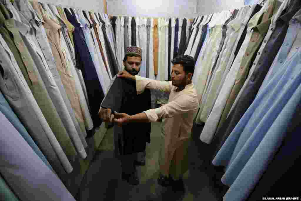 A Pakistani man tries on secondhand clothes ahead of Eid al-Fitr, marking the end of the holy month of Ramadan, in Peshawar.&nbsp;