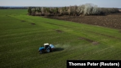 An aerial view shows a tractor spreading fertilizer on a wheat field near the village of Yakovlivka, outside Kharkiv, after it was hit by a Russian aerial bombardment on April 5.