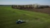 Fotografija iz vazduha prikazuje traktor kako raznosi đubrivo po polju pšenice u blizini sela Jakovlivka kod Harkova, nakon bombardovanja tog područja tokom ruske invazije na Ukrajinu, 5. aprila 2022.
