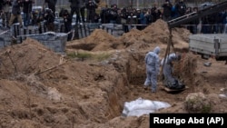 Працівники кладовища ексгумують тіла мирних жителів, убитих у Бучі, з братської могили на околиці Києва, Україна, 13 квітня 2022 року