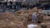 Workers exhume the corpse of a civilian killed in Bucha from a mass grave on April 13.