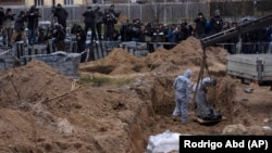 Workers exhume the corpse of a civilian killed in Bucha from a mass grave on April 13.