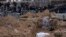 Workers exhume the corpse of a civilian killed in Bucha from a mass grave on April 13.