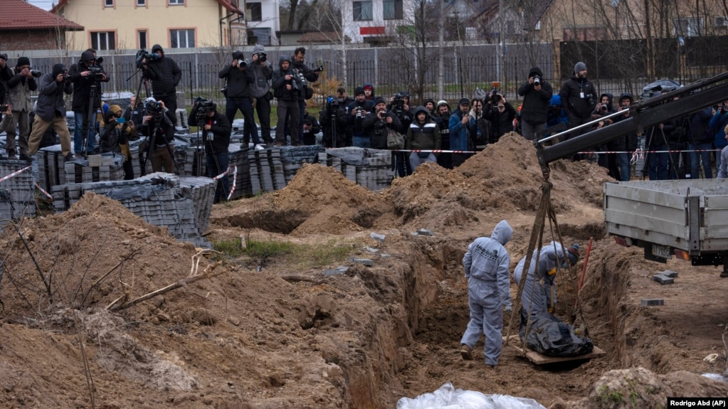Работники кладбища эксгумируют труп мирного жителя, убитого в Буче, из братской могилы на окраине Киева, 13 апреля 2022 года