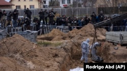 Cemetery workers exhume the corpse of a civilian killed in Bucha, outside Kyiv, from a mass grave in April.