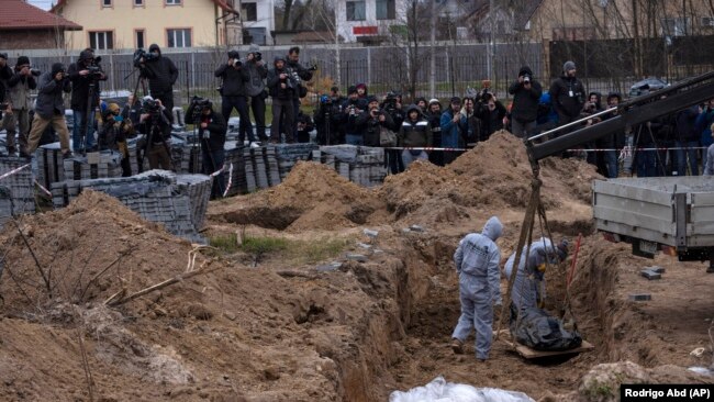 Cemetery workers exhume the corpse of a civilian killed in Bucha, outside Kyiv, from a mass grave in April.