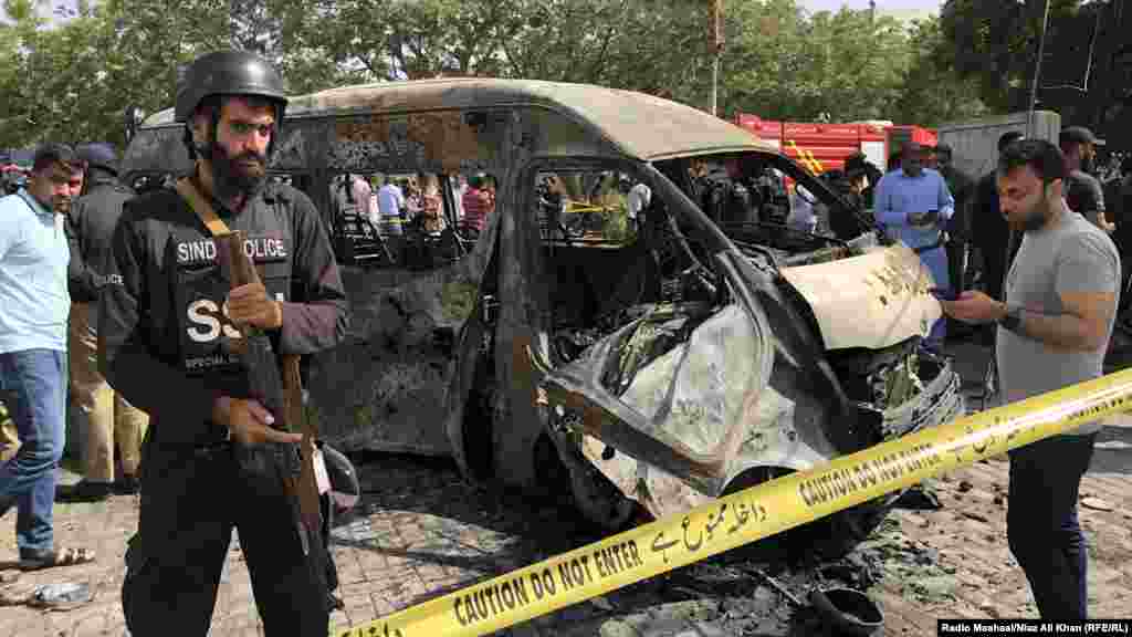 Poliția pakistaneză inspectează zona unde mai multe vehicule au fost distruse într-o explozie în care au fost uciși trei cetățeni chinezi și șoferul lor pakistanez, în apropierea Institutului Chinez de la Universitatea Karachi pe 26 aprilie, potrivit declarațiilor oficiale. (Niaz Ali Khan, Radio Mashaal, RFE/RL)