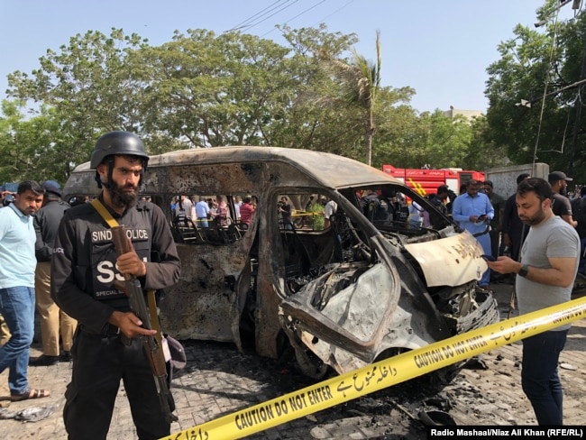 A policeman guards a burnt van after a suicide bombing attack inside Karachi University on April 26.