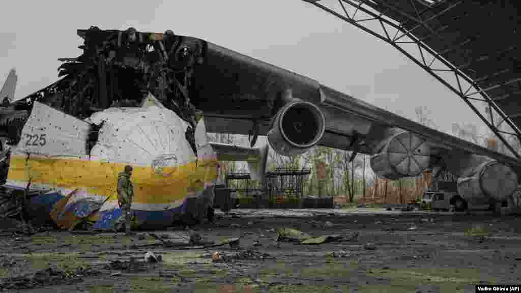 Un soldat ucrainean trece pe lângă rămășițele avionului de transport Antonov An-225 Mriia, 2 aprilie 2022. Mriia, cel mai mare avion din lume, a fost distrus de o lovitură rusă la 27 februarie în timpul luptelor de pe aeroportul Antonov din Hostomel. Mriia, care înseamnă &bdquo;vis&rdquo; sau &bdquo;inspirație&rdquo;, era iubit de pasionații de aviație din întreaga lume.