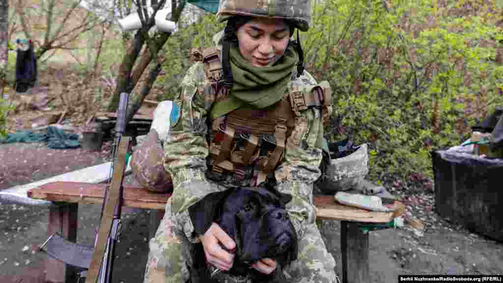 Українська військова Катерина гладить собаку породи Кане Корсу на передовій позиції. 22 квітня 2022 року