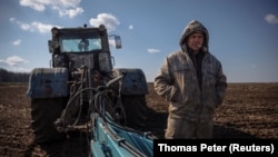 A Ukrainian farmer is seen in a field with a tractor. Ukraine is one of the world's largest suppliers of grain.