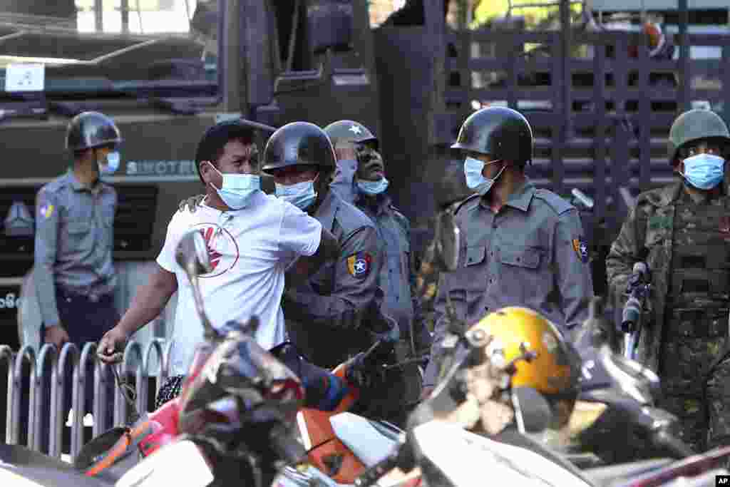 BURMA -- MYANMAR -- A man is held by police during a crackdown on anti-coup protesters holding a rally in front of the Myanmar Economic Bank in Mandalay, Myanmar on Monday, Feb. 15, 2021.