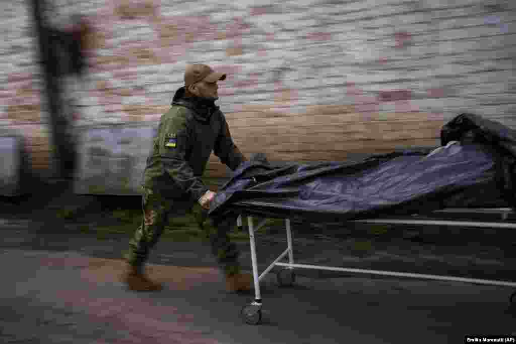 A worker moves dead bodies from refrigerated trucks to a morgue in Bucha, on the outskirts of Kyiv, on April 25, following Russia&#39;s withdrawal from the town.