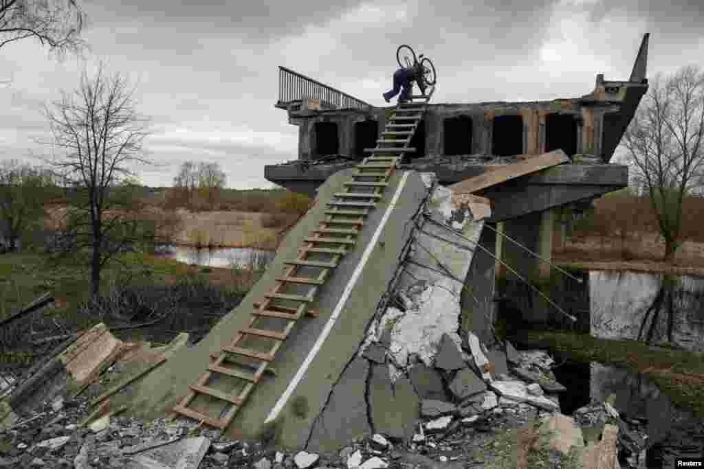 Mikola, egy hetvenéves helyi lakos egy ideiglenes létrán próbál meg lemászni egy felrobbantott híd tetejéről a Kijevi régióban található Kukariban