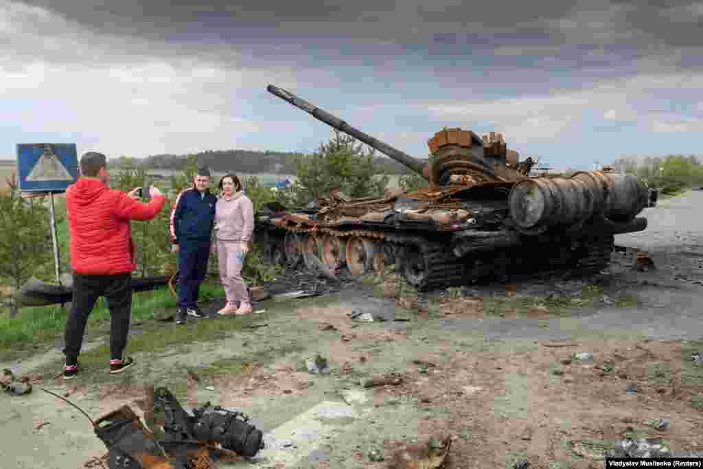 People pose for a picture in front of the debris of Russian military machinery that was destroyed in Ukraine&#39;s Kyiv region.&nbsp;