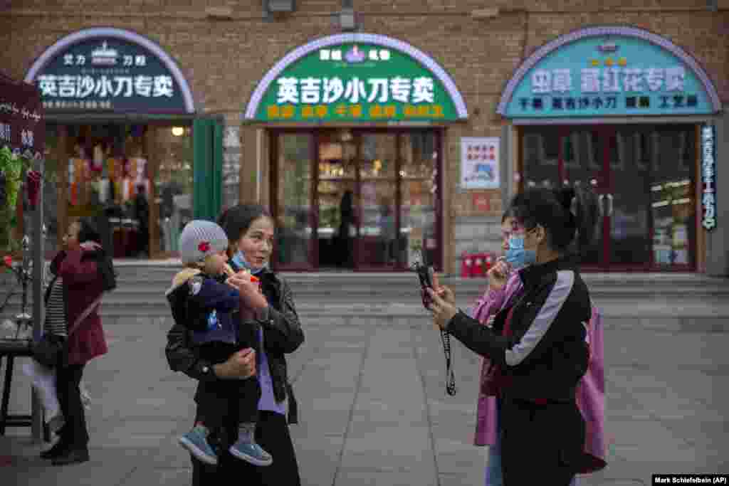 China Xinjiang Daily Life -- A woman poses for a smartphone photo with a child at the International Grand Bazaar in Urumqi in western China's Xinjiang Uyghur Autonomous Region, as seen during a government organized trip for foreign journalists, Wednesday,