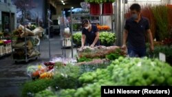Продавачи на плодове и зеленчуци отварят отново своите щандове, носейки маски. Снимката е направена на 14 април във Виена. 