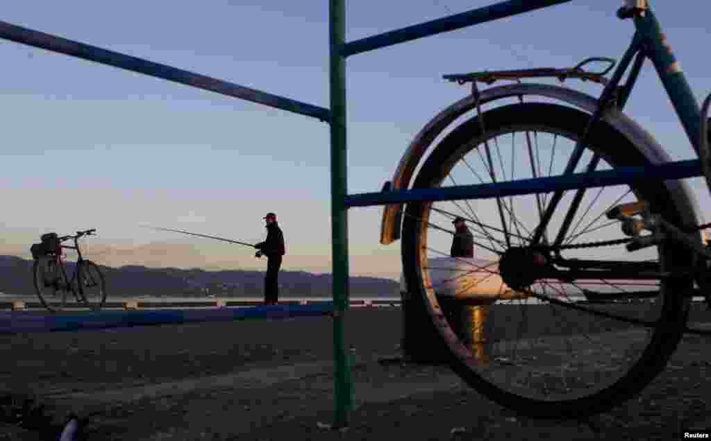 A man fishes on a pier in Sukhumi&#39;s harbor.