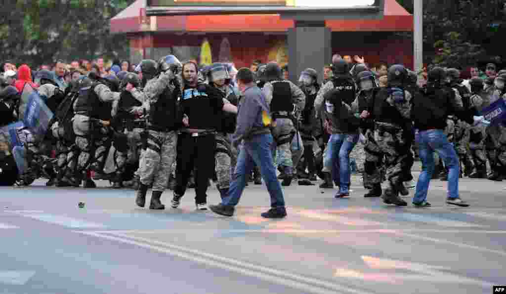 Riot police scuffle with protesters.