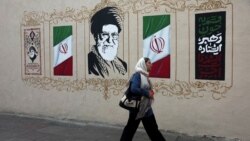 A woman walks by a mural depicting Iran's late Supreme Leader Ayatollah Ali Khamenei on a street in Tehran on August 13.
