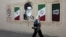 A woman walks by a mural depicting Iran's late Supreme Leader Ayatollah Ali Khamenei on a street in Tehran on August 13.