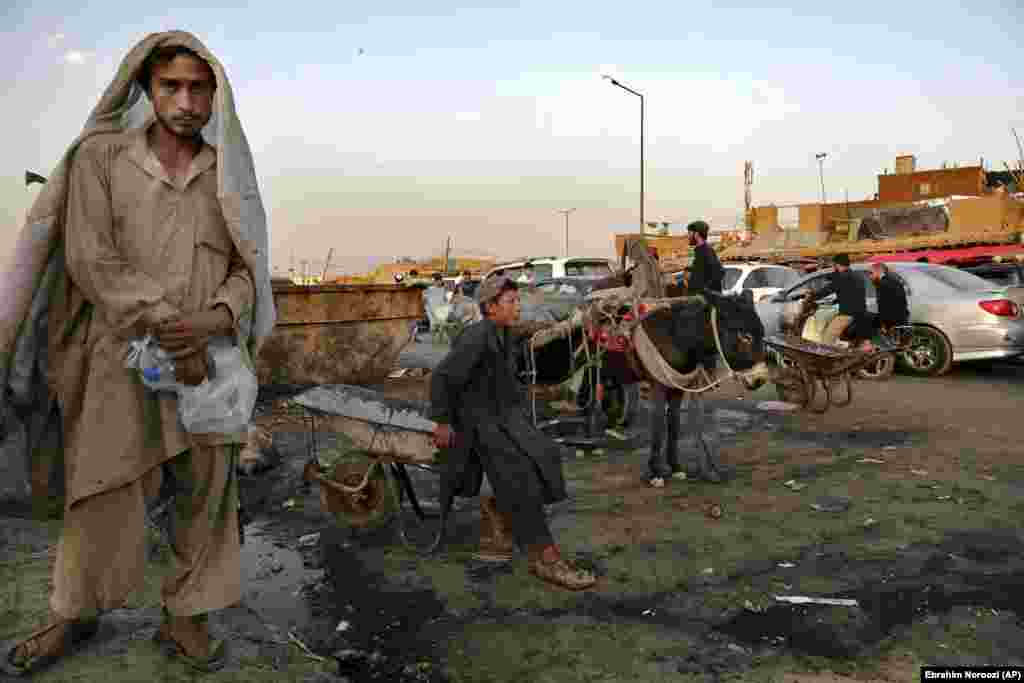 Кабулдун эски шаарындагы базарда колдо жасаган арабасынын үстүндө отурган жаш жумушчу.&nbsp;