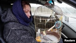 Жена се евакуира од Мариупол, носејќи кафез со папагал