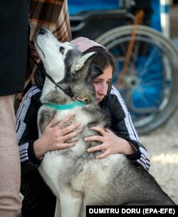 O tânără din Ucraina îmbrățișează un câine la centrul de primire de lângă satul Palanca, la aproximativ trei kilometri de frontiera cu Ucraina, 17 martie 2022.