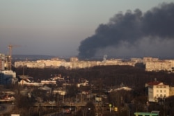 Un fum gros se ridică din clădirea unei uzine de reparații a avioanelor, de lângă aeroportul din Liov, 18 martie 2022.