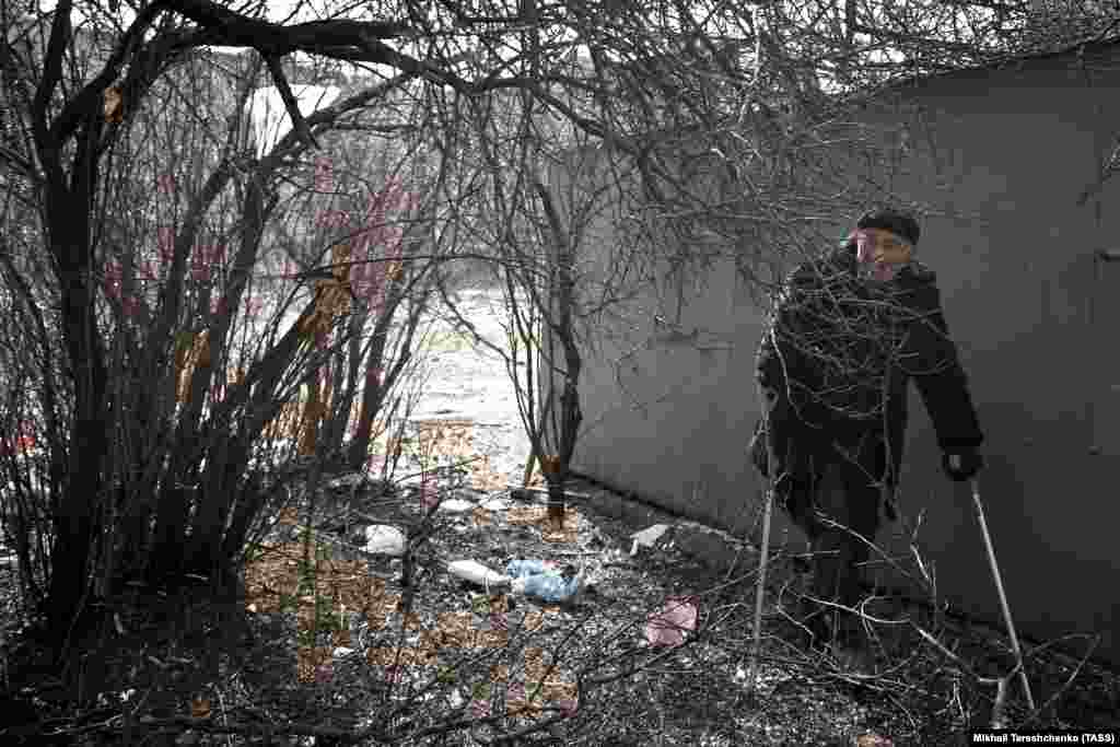 A man takes cover from shelling behind a garage.