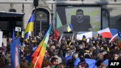 Ukrainian President Volodymyr Zelenskiy is displayed on a giant screen after delivering a live voice message during a demonstration against the Russian invasion of Ukraine in front of the Swiss parliament in Bern on March 19, 2022. 