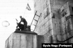 A szovjet katona szobrának ledöntése után Mikó József operatőr magyar zászlót tűz a szobor csizmájába egy fiatal katona segítségével