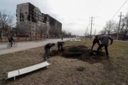 Banorët në Mariupol hapin varre për të varrosur personat e vrarë. 20 mars 2022.