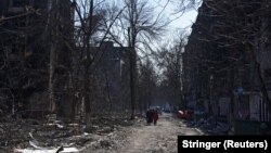 Місцеві жителі серед будинків, пошкоджених російськими обстрілами, у Маріуполі, 18 березня 2022 року