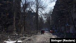 Місцеві жителі серед будинків, пошкоджених російськими обстрілами, у Маріуполі, 18 березня 2022 року