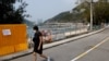 Žena prolazi pored ograda postavljenih da blokiraju pristup plaži Deep Water Bay tokom pandemije korona virusa , u Hong Kongu, Kina, 18. marta 2022.
