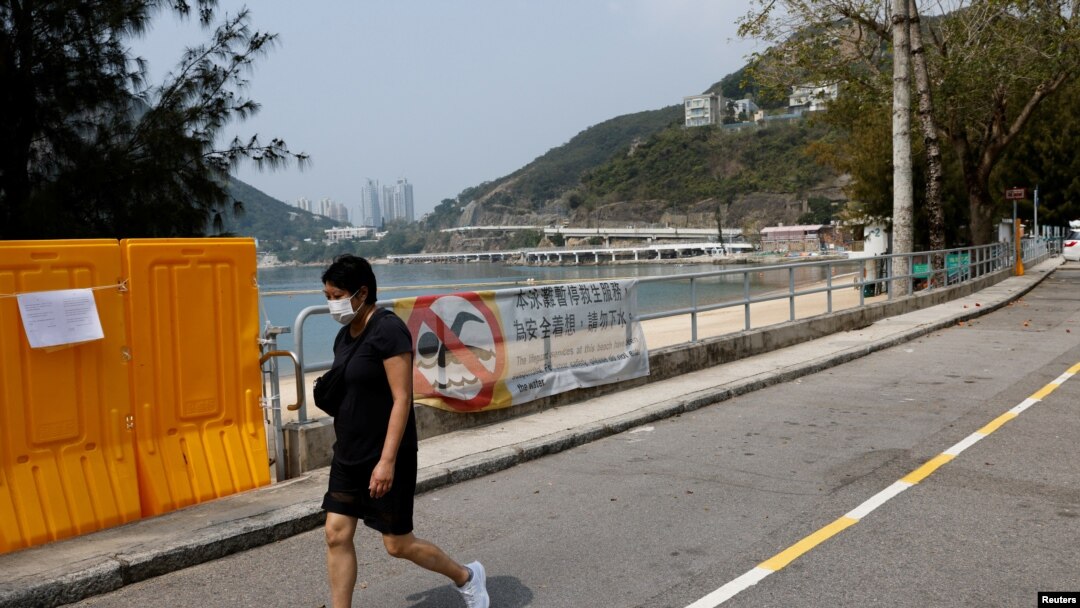 Žena prolazi pored ograda postavljenih da blokiraju pristup plaži Deep Water Bay tokom pandemije korona virusa , u Hong Kongu, Kina, 18. marta 2022.
