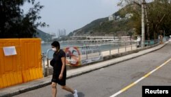 Žena prolazi pored ograda postavljenih da blokiraju pristup plaži Deep Water Bay tokom pandemije korona virusa , u Hong Kongu, Kina, 18. marta 2022.