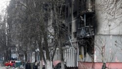 Localnicii trec pe lângă o clădire bombardată de trupele ruse, Mariupol, 18 martie, 2022.